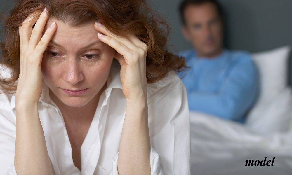 Female with Jaw Pain Holding Face at the Foot of the Bed